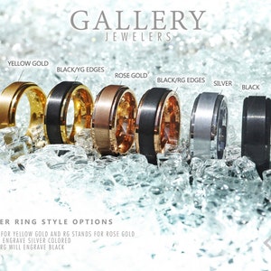 May include: Six different styles of spinner rings with various metal finishes. The rings are arranged from left to right: yellow gold, black with yellow gold edges, rose gold, black with rose gold edges, silver, and black. The rings are displayed on a bed of crushed ice.