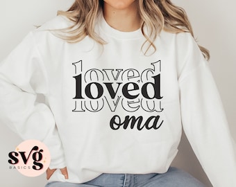 May include: White sweatshirt with black text that reads "loved oma" in a layered, overlapping font style.