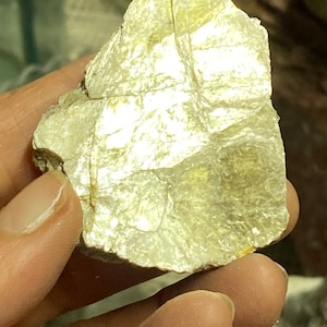 May include: A large, irregularly shaped piece of mica with a silvery-white, iridescent sheen. The mica has a layered, flaky texture and is translucent.
