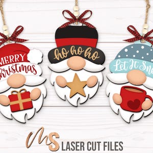 May include: Three wooden Christmas gnome ornaments. Each gnome has a different hat and design. One says "Merry Christmas" with a gift, another says "ho ho ho" with a star, and the last says "Let It Snow" with a mug.