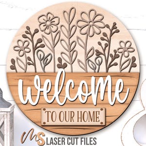 SVG Laser Cut Files for a round wood Floral Welcome Sign featuring a row of flowers filling the top half of the sign with a bottom panel that looks like a wood crate with the greeting Welcome To Our Home in decorative fonts. Make DIY Wildflower Door Hangers, Front Door Decor and Floral Porch Door Signs for spring and summer decor!