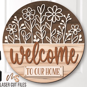 SVG Laser Cut Files for a round wood Floral Welcome Sign featuring a row of flowers filling the top half of the sign with a bottom panel that looks like a wood crate with the greeting Welcome To Our Home in decorative fonts. Make DIY Wildflower Door Hangers, Front Door Decor and Floral Porch Door Signs for spring and summer decor!
