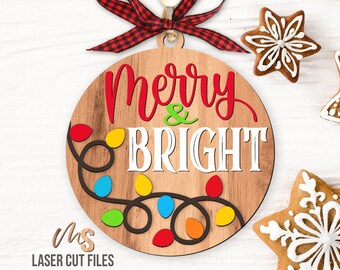 May include: A round wooden ornament with the text "Merry & Bright" in red and white lettering. The ornament is decorated with a string of colorful lights.