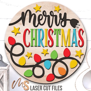Puede incluir: Letrero navideño de madera con las palabras "Merry Christmas" en escritura negra y letras de colores. El diseño incluye estrellas amarillas y una guirnalda de luces navideñas de colores. El letrero tiene un diseño de enchufe.