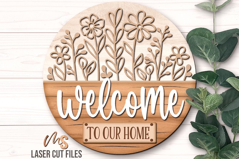 SVG Laser Cut Files for a round wood Floral Welcome Sign featuring a row of flowers filling the top half of the sign with a bottom panel that looks like a wood crate with the greeting Welcome To Our Home in decorative fonts. Make DIY Wildflower Door Hangers, Front Door Decor and Floral Porch Door Signs for spring and summer decor!
