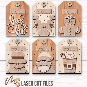 SVG Laser Cut Files for a bundle of 6 Christmas Gift Card Holders featuring cute Gift Tag shapes decorated with a Santa Claus, the text Ho Ho Ho, a Snowman, a Gingerbread Man, a Reindeer, and a Christmas Coffee Cup with spacers on the inside where you can insert your Gift Cards and money! Create festive Gift Card Holders, Money Holders, and gift Ornaments!
