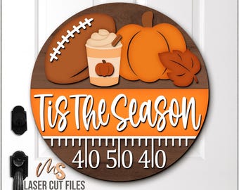 May include: A round wooden sign with a football, pumpkin, and coffee cup design. The sign reads "Tis The Season" in white script over an orange background. The bottom has yard markers.