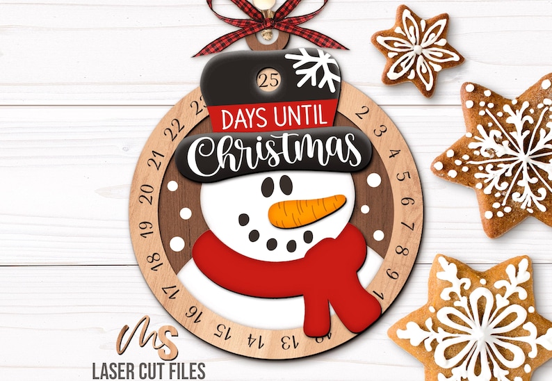 SVG Laser Cut Files for a Christmas Countdown Snowman Ornament featuring a cute snowman wearing a scarf and top hat adorned with a snowflake. His scarf covers a round turning wheel with 25 numbered days until Christmas, and his hat provides a window at the top to show how many days you have left! Turn the wheel each day until you reach the snowflake on Christmas morning!