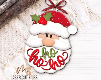 May include: A wooden Santa Claus face ornament with a red and white polka-dot hat, white beard, and the words "ho ho ho" in red and green. The ornament has a red and black plaid ribbon for hanging.