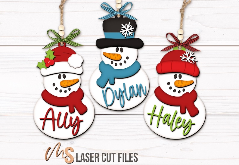 SVG Laser Cut Files for a bundle of three cute Snowman Ornaments wearing a santa hat, snowman hat, and winter beanie cap with scarfs, snowflakes, and an open space to add your own custom text and names. Perfect for making custom Christmas Ornaments, Christmas Gift Tags and Name Tags for the holidays!