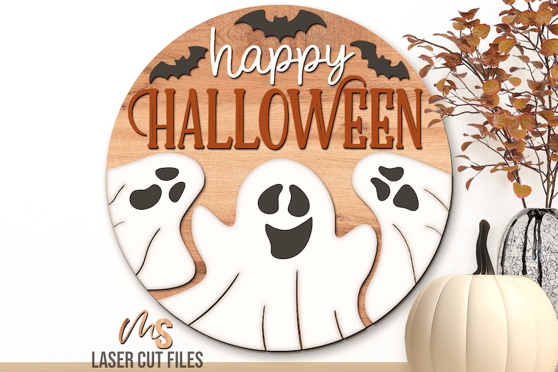 SVG files for a round wood Halloween Sign with three spooky ghosts peaking up from the bottom with the phrase Happy Halloween in decorative fonts and bats flying overhead. Perfect for making spooky Halloween Door Hangers, Ghost Signs, and Halloween decor this fall season!
