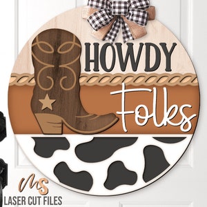 May include: A round wooden sign with a brown cowboy boot, a brown rope design, and the text "Howdy Folks" in black and white. The bottom of the sign has a black and white cow print design.