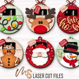 SVG Laser Cut Files for a bundle of 6 Christmas Gift Card Holders shaped like ornaments decorated with a Santa Claus, the text Ho Ho Ho, a Snowman, a Gingerbread Man, a Reindeer, and a string of Christmas lights with spacers on the inside where you can insert your Gift Cards and money, and an additional tag which says Merry Christmas or add your own custom name for personalization! Create festive Gift Card Holders, Money Holders, and gift Ornaments!