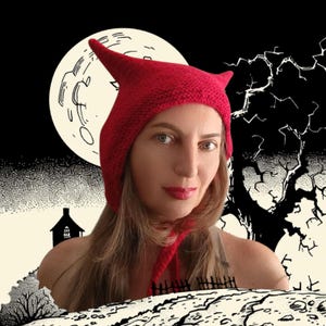 May include: A red knitted hat with pointed ears and ties. The hat is worn by a person in front of a black and white Halloween-themed background with a full moon, a spooky tree, and a silhouette of a house.