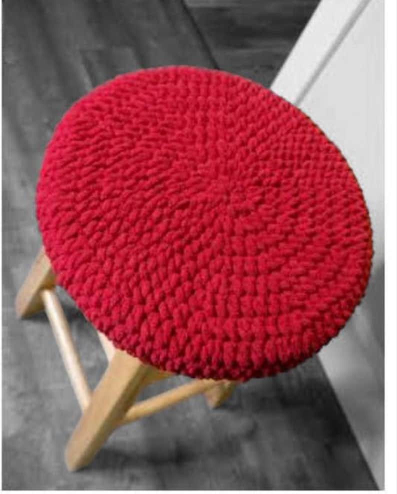 Puede incluir: Coj&iacute;n de silla de crochet rojo. El coj&iacute;n es redondo y tiene una superficie texturizada.