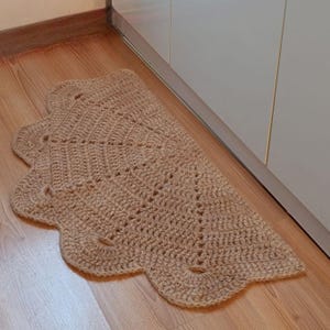 May include: A brown, crocheted, half-circle rug with a scalloped edge. The rug is made of natural fibers and has a rustic, handmade look.