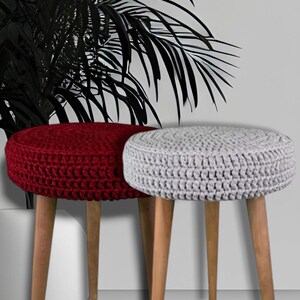 Puede incluir: Dos otomanas redondas de crochet con patas de madera. Una otomana es roja y la otra es gris.