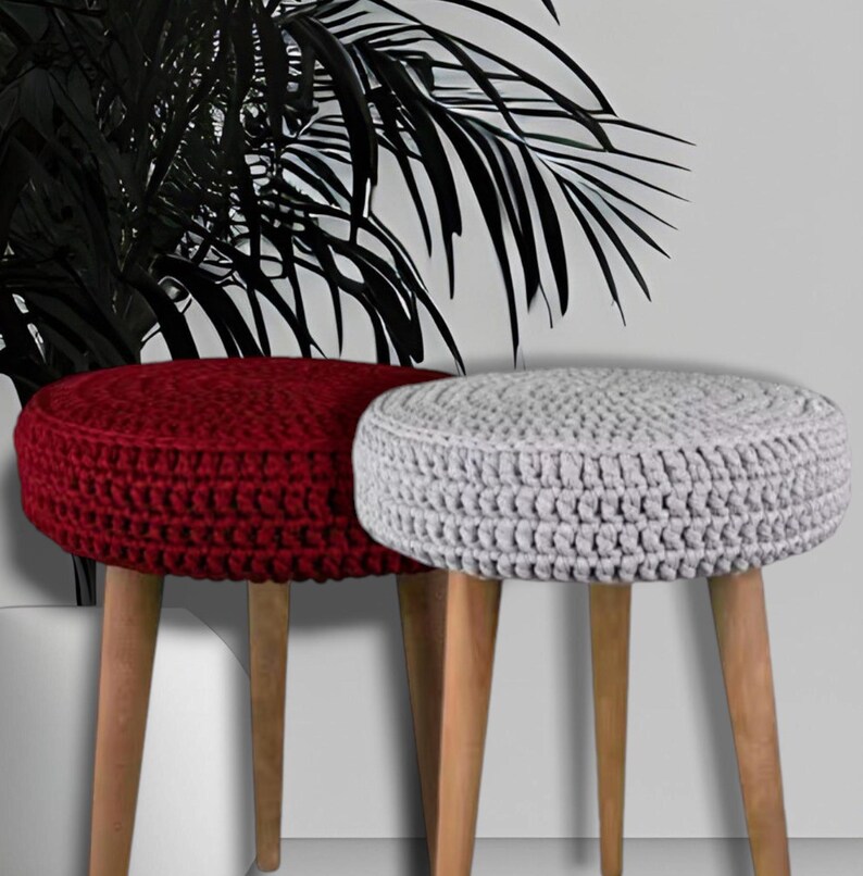 Puede incluir: Dos otomanas redondas de crochet con patas de madera. Una otomana es roja y la otra es gris.