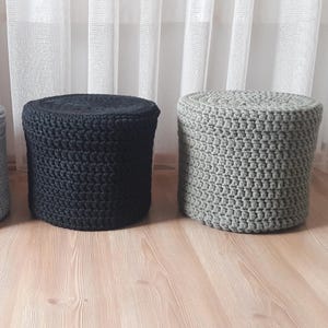 Puede incluir: Tres otomanas redondas de crochet en negro, gris y blanco. Las otomanas est&aacute;n hechas de cuerda gruesa y tienen una superficie texturizada.
