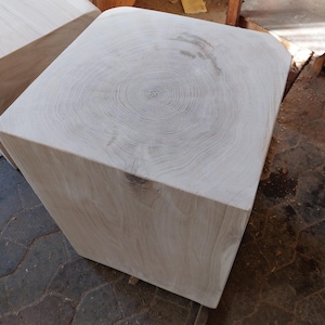 Puede incluir: Un bloque de madera grande, cuadrado, con un acabado de madera clara. La parte superior del bloque tiene un patrón de veta circular.