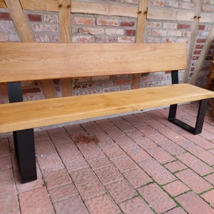 K&ouml;nnte beinhalten: Eine Holzbank mit naturbelassenem Finish und schwarzen Metallbeinen. Die Bank ist aus massivem Holz gefertigt und hat ein schlichtes, modernes Design.