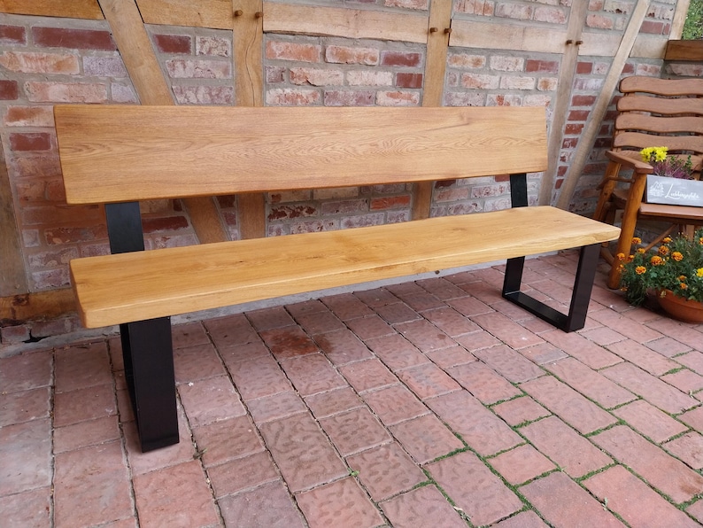 K&ouml;nnte beinhalten: Eine Holzbank mit naturbelassenem Finish und schwarzen Metallbeinen. Die Bank ist aus massivem Holz gefertigt und hat ein schlichtes, modernes Design.