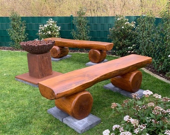 Könnte beinhalten: Zwei Holzbänke mit abgerundeten Kanten und Beinen im Baumstammstil, auf einem Rasen mit einer Metallsculptur im Hintergrund.
