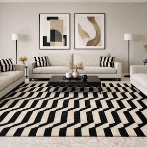 Peut inclure: Salon moderne avec un canapé crème, une table basse noire et un tapis à motifs noir et blanc. Deux œuvres d'art abstraites encadrées sont accrochées au-dessus du canapé. Des coussins rayés noirs et blancs ornent le canapé.