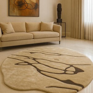 Pode incluir: Um tapete redondo bege com um design org&acirc;nico &uacute;nico. O tapete apresenta uma base bege mais clara com padr&otilde;es castanhos escuros e fluidos. O tapete est&aacute; colocado numa sala de estar com um sof&aacute; bege e uma obra de arte abstrata. O di&acirc;metro do tapete &eacute; de cerca de 250 cm.