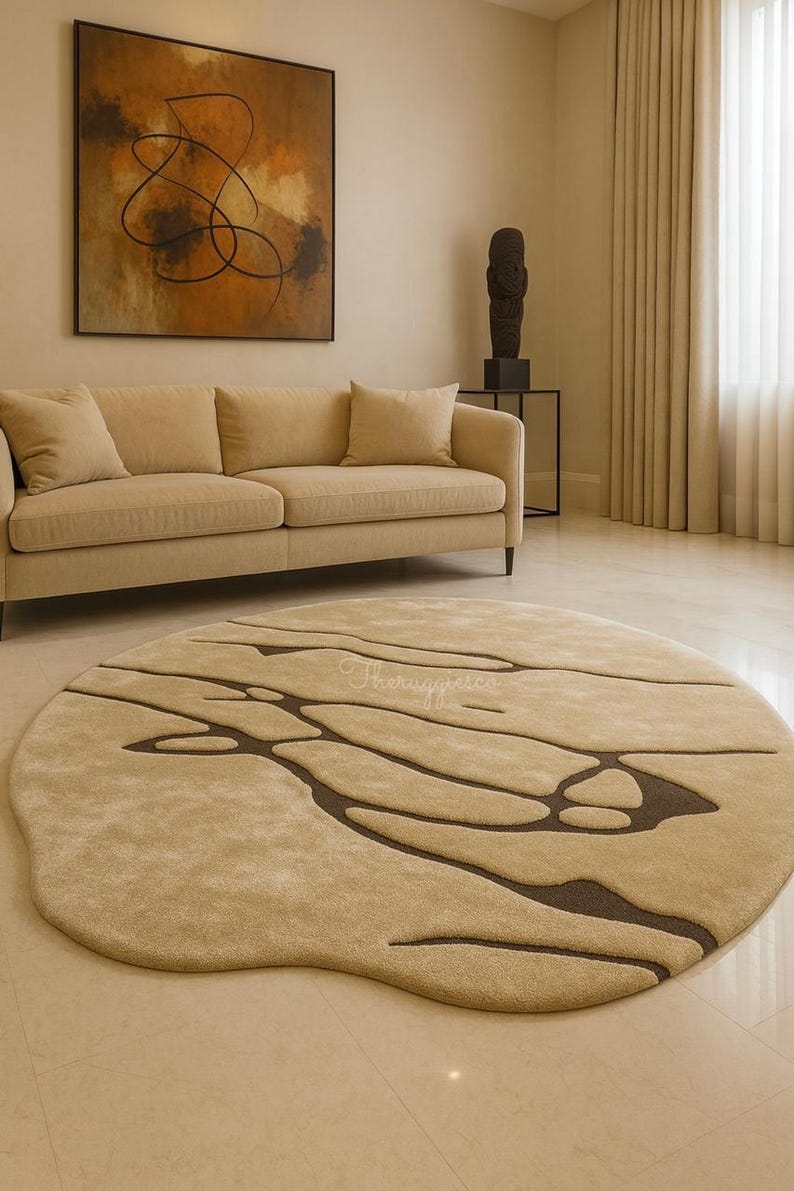 Pode incluir: Um tapete redondo bege com um design org&acirc;nico &uacute;nico. O tapete apresenta uma base bege mais clara com padr&otilde;es castanhos escuros e fluidos. O tapete est&aacute; colocado numa sala de estar com um sof&aacute; bege e uma obra de arte abstrata. O di&acirc;metro do tapete &eacute; de cerca de 250 cm.