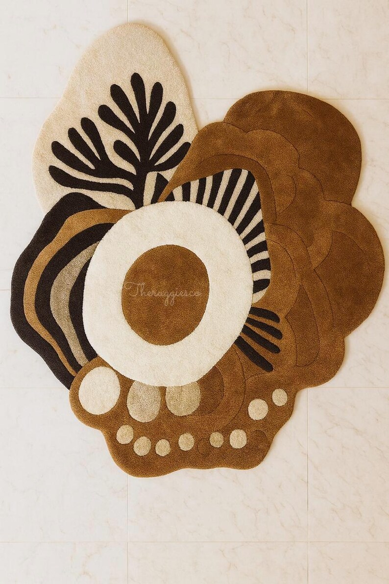 May include: An abstract, multi-colored rug with a floral design. The rug features a cream-colored background with brown, black, and tan accents. The rug has a unique shape and texture, with a variety of patterns and shapes.