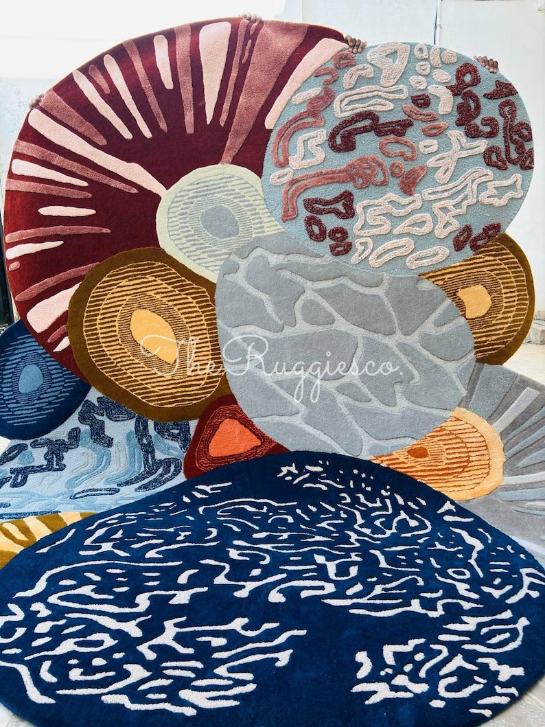 May include: A collection of colorful, round rugs with various abstract designs. The rugs feature a range of colors, including deep red, blue, brown, and gray, with patterns like concentric circles and organic shapes. The rugs are arranged in a visually appealing display.