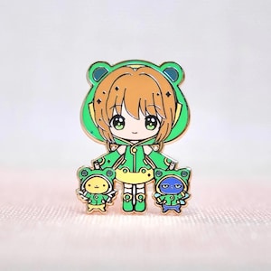 Broche de esmalte com capa de chuva de sapo Sakura – Broche fofo de chibi com Kero e Suppi, arte de fã de mascote de garota mágica, presente inspirado em anime kawaii