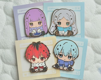 Könnte beinhalten: Vier Emaille-Anstecknadeln mit Anime-Charakteren mit großen Augen und bunten Haaren. Jede Anstecknadel befindet sich auf einer pastellfarbenen Karte mit dem Text "KOMAKIS". Die Charaktere haben blaue, lila, rote und weiße Haare und tragen Schals und Outfits in passenden Farben.