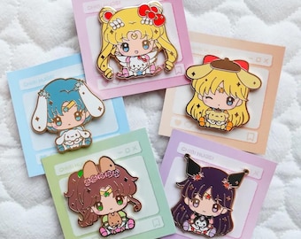 May include: Five enamel pins featuring characters from the anime Sailor Moon. Each pin features a different Sailor Scout holding a small plush animal. The pins are on a pastel background with the text "Chibi Hugs!" on each card.