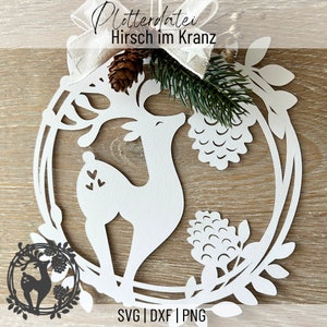 May include: White paper cut-out of a deer in a wreath with the text "Plotterdatei Hirsch im Kranz" and "SVG | DXF | PNG" at the bottom.