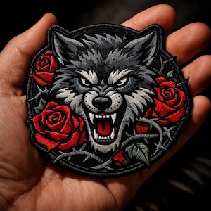 May include: Embroidered patch featuring a snarling wolf's head with sharp teeth, surrounded by red roses and thorny vines. The wolf has gray and black fur, with a fierce expression. The patch is circular with a black border.