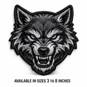 May include: Embroidered patch featuring a detailed, snarling wolf head in black and white. The wolf's teeth are bared, and its eyes are intense. Text at the bottom reads "AVAILABLE IN SIZES 3 TO 8 INCHES."
