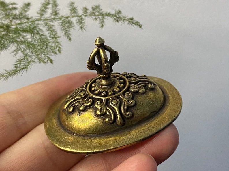 May include: A detailed, antique-style brass lid with an ornate design. The lid features a central crown-like handle and intricate floral patterns around the edge. The brass has a warm, aged patina, suggesting it is vintage or vintage-inspired.