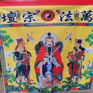 May include: A yellow banner with Chinese characters and illustrations of three figures in traditional robes. The banner features a yin-yang symbol and two cranes. The top and bottom borders are red and blue.