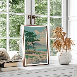 May include: A framed print of a Japanese landscape painting depicting a mountain, a boat on a beach, and two pine trees. The print is in a brown frame and is hanging on a white wall.