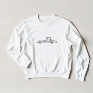 Könnte beinhalten: Weißes Sweatshirt mit Rundhalsausschnitt und einer schwarzen Strichzeichnung eines klassischen Sportwagens. Das Auto ist im Profil dargestellt und zeigt sein elegantes Design. Das Sweatshirt besteht aus weichem Material und hat lange Ärmel.