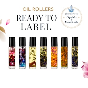 Op de afbeelding: Zeven doorzichtige glazen rollerflesjes met zwarte doppen, gevuld met diverse botanische elementen en gouden stervormen. De tekst luidt OIL ROLLERS READY TO LABEL en CRAFTED WITH Crystals & Botanicals. De flesjes bevatten kleurrijke gedroogde bloemen.
