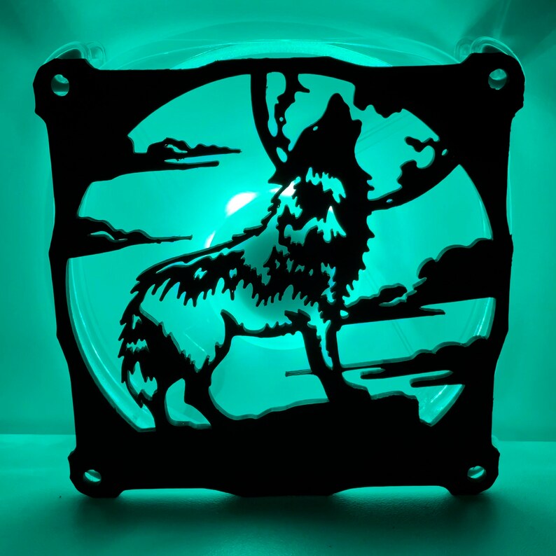 May include: A black silhouette of a wolf howling at the moon, cut out of a clear plastic fan. The fan is illuminated with a bright green light.