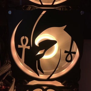 Peut inclure: Un ventilateur de boîtier d'ordinateur noir avec une lumière blanche et un design stylisé d'un dauphin et d'un symbole Ankh.