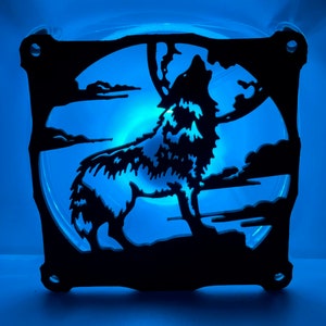 May include: A black silhouette of a wolf howling at the moon, cut out of a computer fan. The fan is illuminated with blue light.