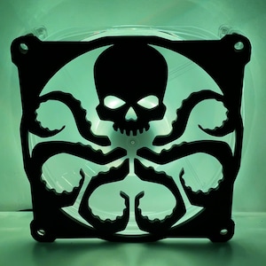 Könnte beinhalten: Ein schwarzer Plastiklüfter mit einem Totenkopf- und Tentakeldesign. Der Lüfter wird von hinten mit grünem Licht beleuchtet.