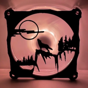 May include: A black silhouette of a wolf howling at the moon, with trees and a mountain range in the background. The image is on a clear, pink acrylic fan.