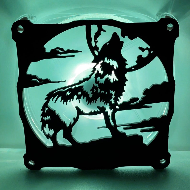 May include: A black computer fan with a silhouette of a wolf howling at the moon. The fan is illuminated from behind, creating a glowing effect.