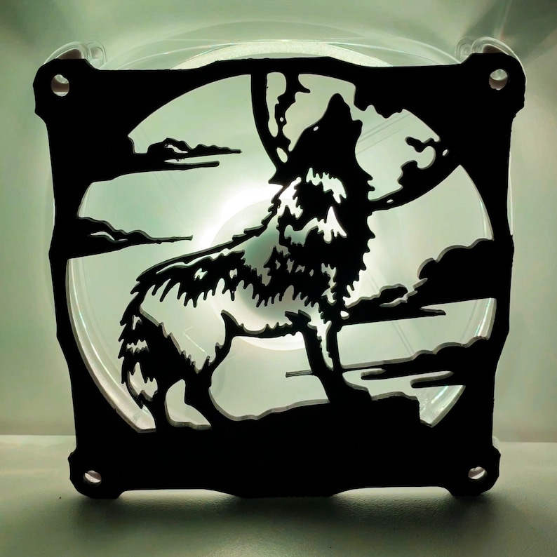 May include: A black silhouette of a wolf howling at the moon, cut out of a clear plastic fan. The wolf is facing the right side of the image and is howling with its mouth open. The moon is behind the wolf and is partially obscured by the wolf's head.